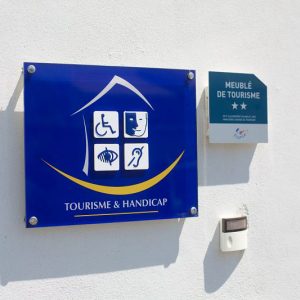 panneau tourisme et handicap à l'entrée d'un gîte conçu pour les personnes en situation de handicap